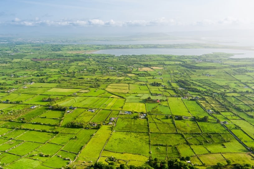 Aerial view of endless lush pastures and farmlands of Ireland. Beautiful Irish countryside with emerald green fields and meadows. Rural landscape.